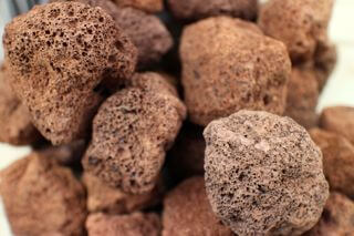 Close-up of several brown volcanic rocks with a rough, porous texture. The rocks are piled together, showcasing their irregular shapes and surfaces.