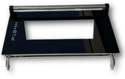 A flat, black rectangular device with a central cutout and metallic clips at the bottom, resembling a laptop stand or holder. The top has a cylindrical silver rod. Partially visible logo on the left side.