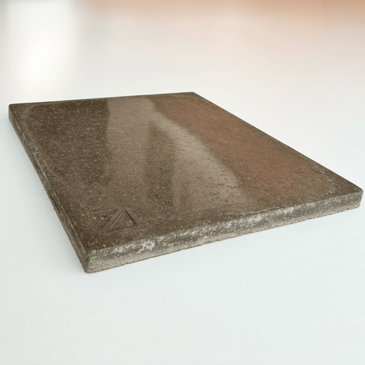 A square, brown tile with a slight texture and subtle stone-like look sits on a white surface. An embossed Z in one corner, its reminiscent of the Effeuno Biscotto Clay Pizza Stone and is perfect for crafting Neapolitan pizza or as a baking stone.
