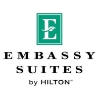 Logo for Embassy Suites by Hilton, featuring a green square with a white E and a leaf design. Below, EMBASSY SUITES by HILTON is written in black text.