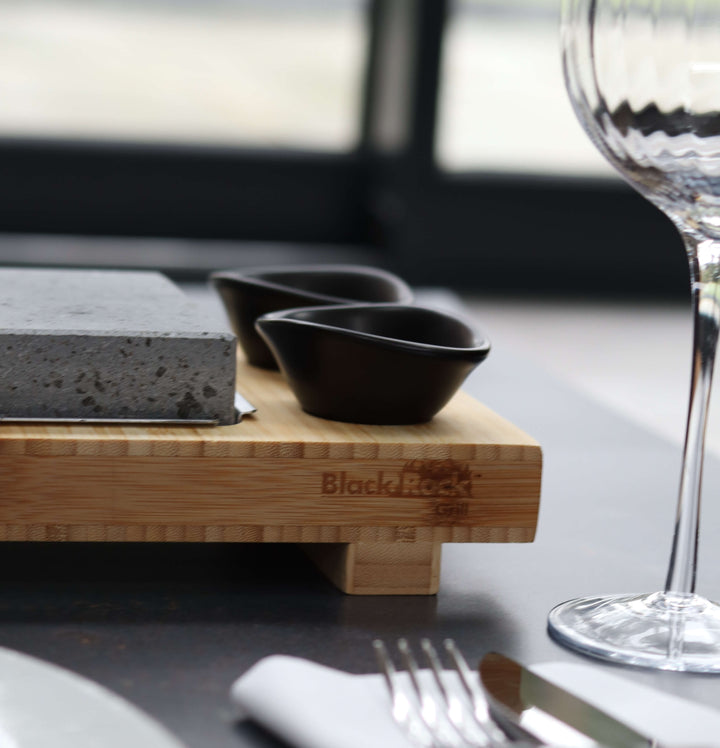 close up of the side of the wooden platetrand dipping pot on a dinner plate