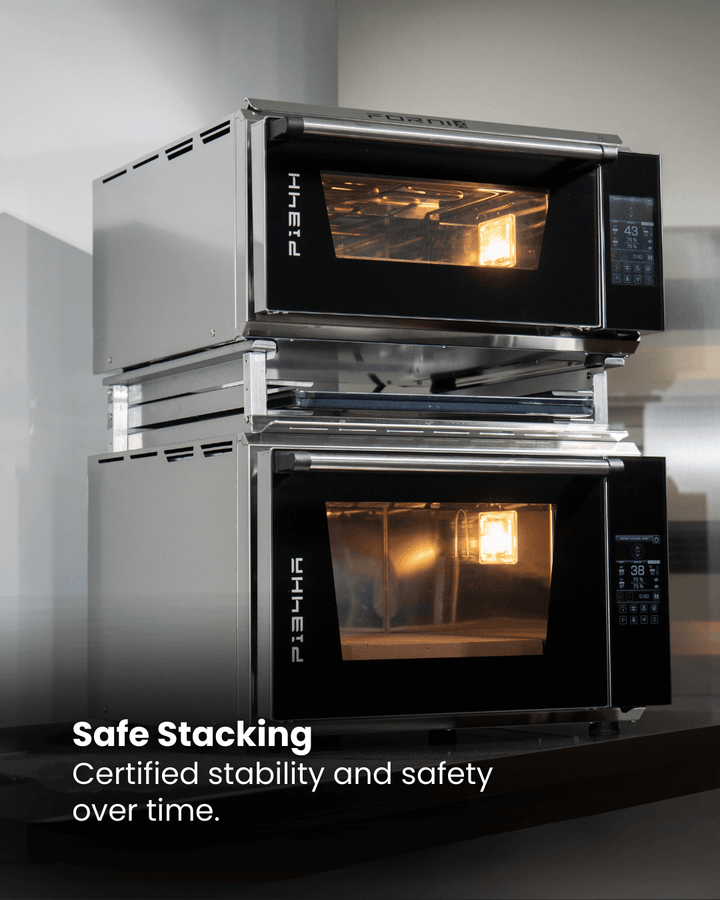 Two Effeuno ovens are stacked with the Black Rock Grill Stacking Kit, both interior lights on. Text: Safe Stacking. Certified stability and safety over time with the Effeuno Stacking Kit for PRO & Evolution Ovens by Black Rock Grill.