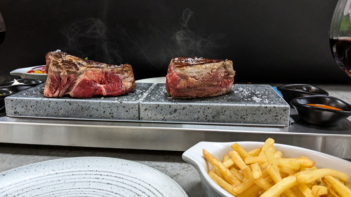 view of the hot rock in action showing the nice thick juicy steaks cooking on the rock