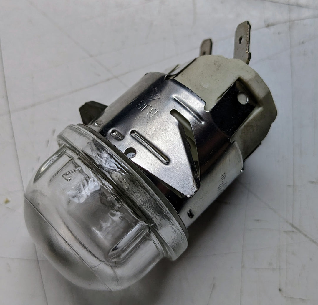 A close-up of the Effeuno Complete Round Lamp Holder, featuring an old-style clear bulb with a metal and plastic base similar to a miniature lamp holder, reveals multiple flat metal prongs. The bulb is placed on a white surface.