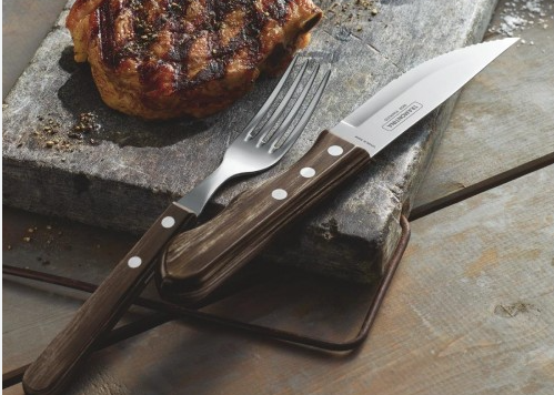 tramontina jumbo steak knfe and fork laid next to steak on a rock