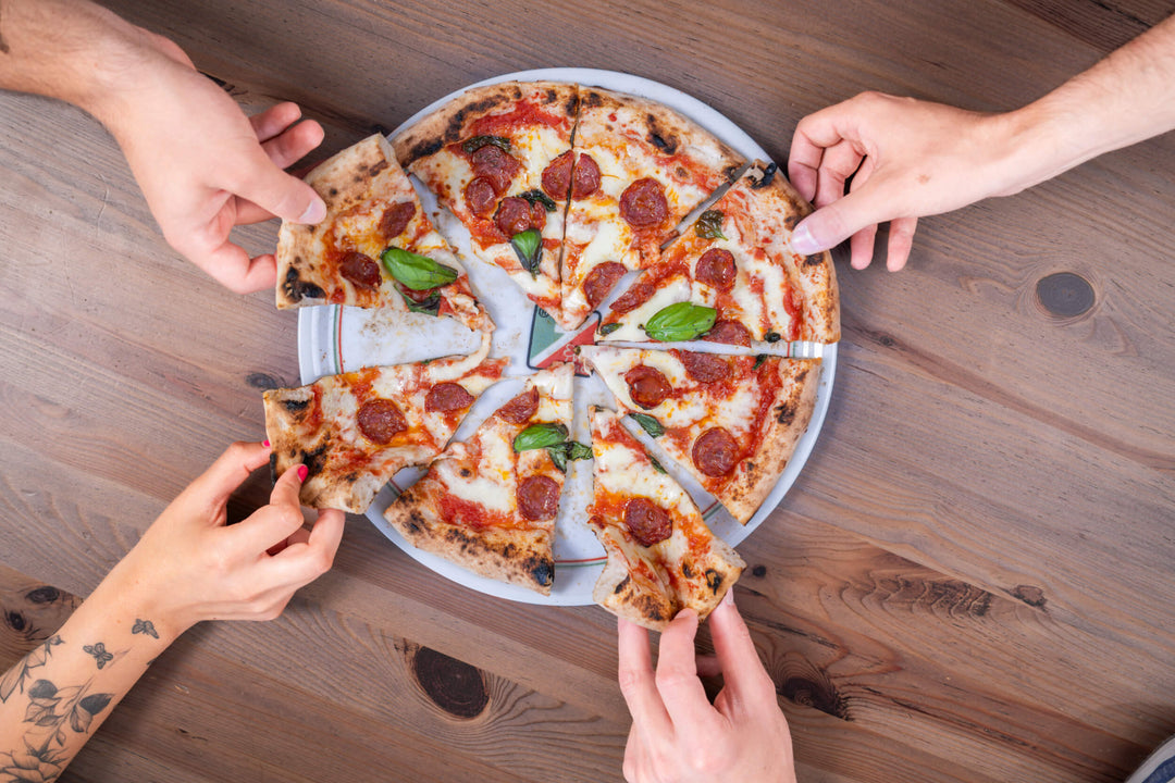 Birds eye view of pizza. Slices are being grabbed by hands