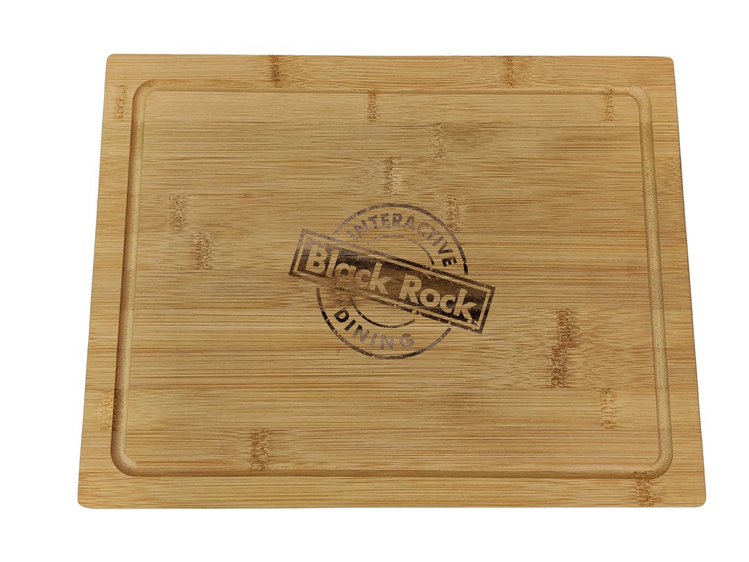 A 30x20x1.2cm rectangular wooden serving board with groove-edged design, featuring a circular Interactive Dining and Black Rock Grill logo in the center, customized with laser engraving. Available in a multi-pack of 24 boards.