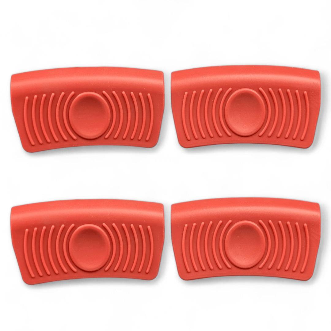 Four red silicone grip handles from Black Rock Grill, each with a central circular indentation and side grooves, are arranged in two rows on a white background. Designed for the Large Reversible Cast Iron Griddle Pan (46cm x 23cm) with marinating oil brush.
