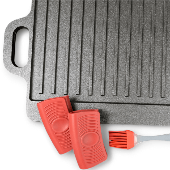 The Black Rock Grill Large Reversible Cast Iron Griddle Pan (46cm x 23cm) features silicone grip handles and comes with a red silicone marinating oil brush—ideal for gas, electric hob, or oven cooking.