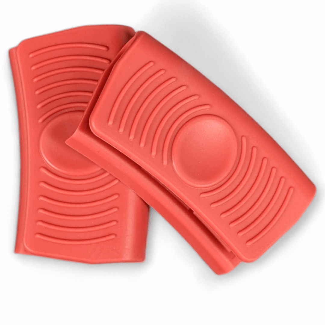 Two Black Rock Grill Silicone Heat Resistant Handle Holder Covers (Pair)—premium food-grade, red, rectangular grips with textured lines—are stacked on a white background, ideal as non-slip protectors for hot cookware handles.