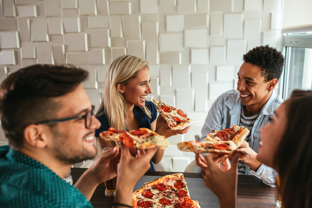 friends enjoying pizza round
 the table