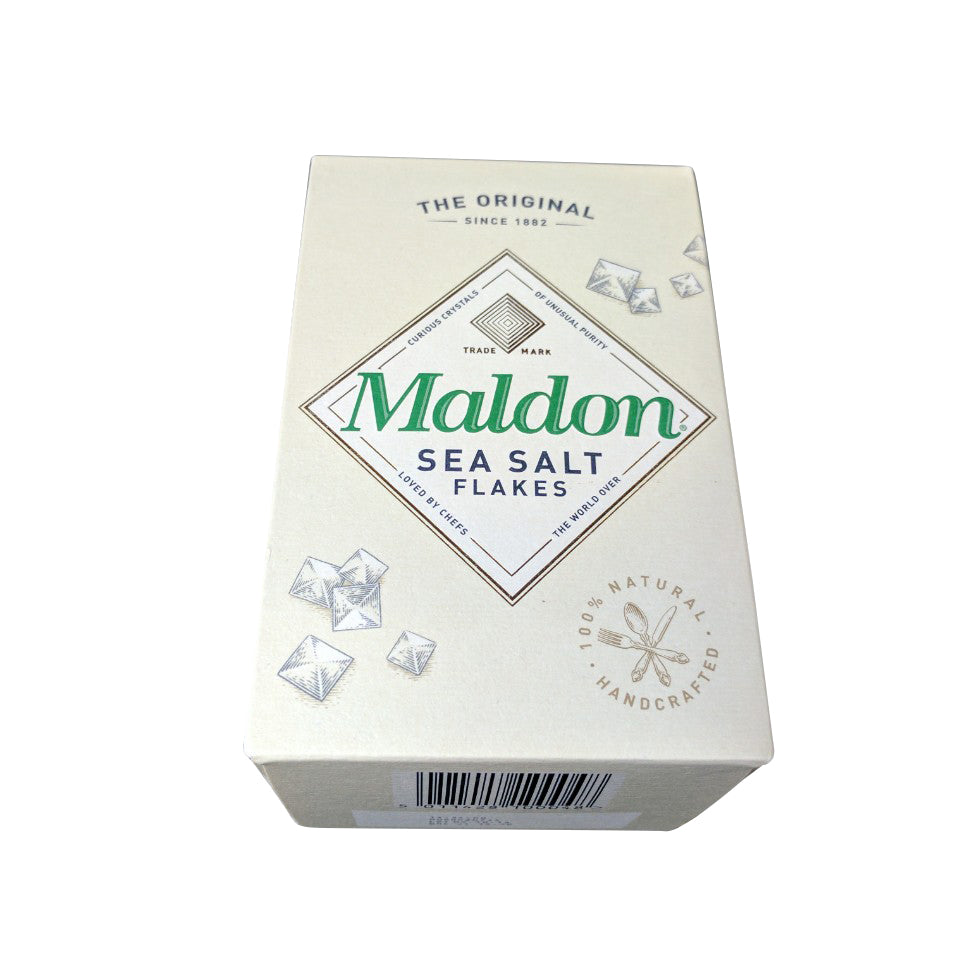 A white Maldon Sea Salt Flakes box with green and black lettering, featuring a diamond logo, salt flakes illustrations, and text like The Original, Since 1882, 100% Natural, and Handcrafted. Ideal for healthy dining. Perfect alongside Black Rock Grills ROXY12 setup for an enhanced dining experience.
