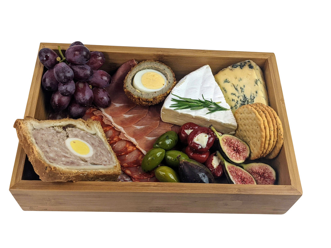 Enjoy a beautifully crafted Bamboo Wooden food presentation tray by Black Rock Grill, filled with gourmet delights like grapes, a meat pie slice with egg, cured meats, brie, blue cheese, crackers, stuffed peppers, olives, and figs for an impeccable display.