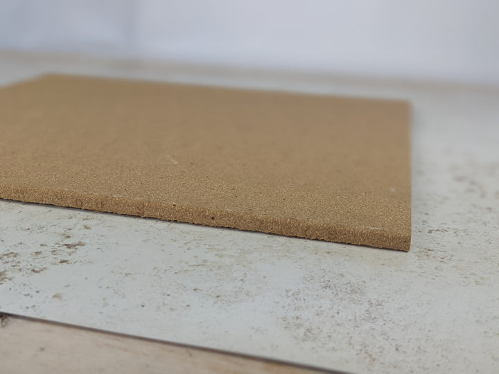A flat, rectangular Refractory Stone for Pizza Oven by Black Rock Grill lays on a speckled white and gray surface reminiscent of a Roxy 12 oven. The blurred, light background suggests an indoor setting. The stone appears unused and in good condition.