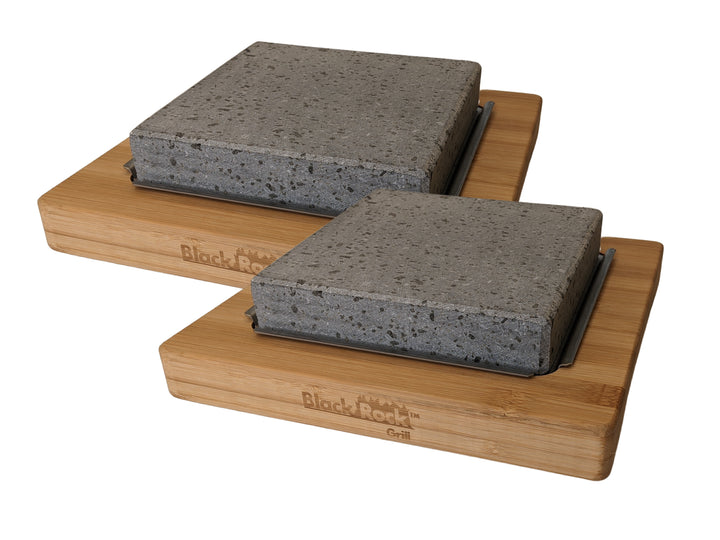 The NEW Black Rock Grill Lava Stone Steak Multi Pack includes two rectangular black rock grills, perfect for hot stone cooking, with thick stone slabs elegantly set on bamboo platters. These bases proudly feature the engraved Black Rock Grill brand name.