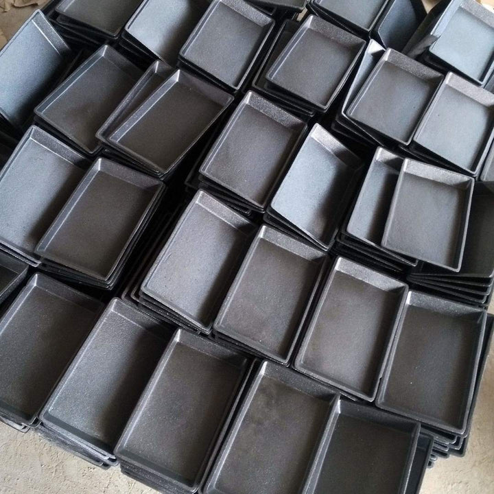A top view shows a stack of Black Rock Grill’s Fajita Cast Iron Skillet Set (12 pieces), featuring rectangular trays with raised edges in solid matte black, resembling sizzler pans.