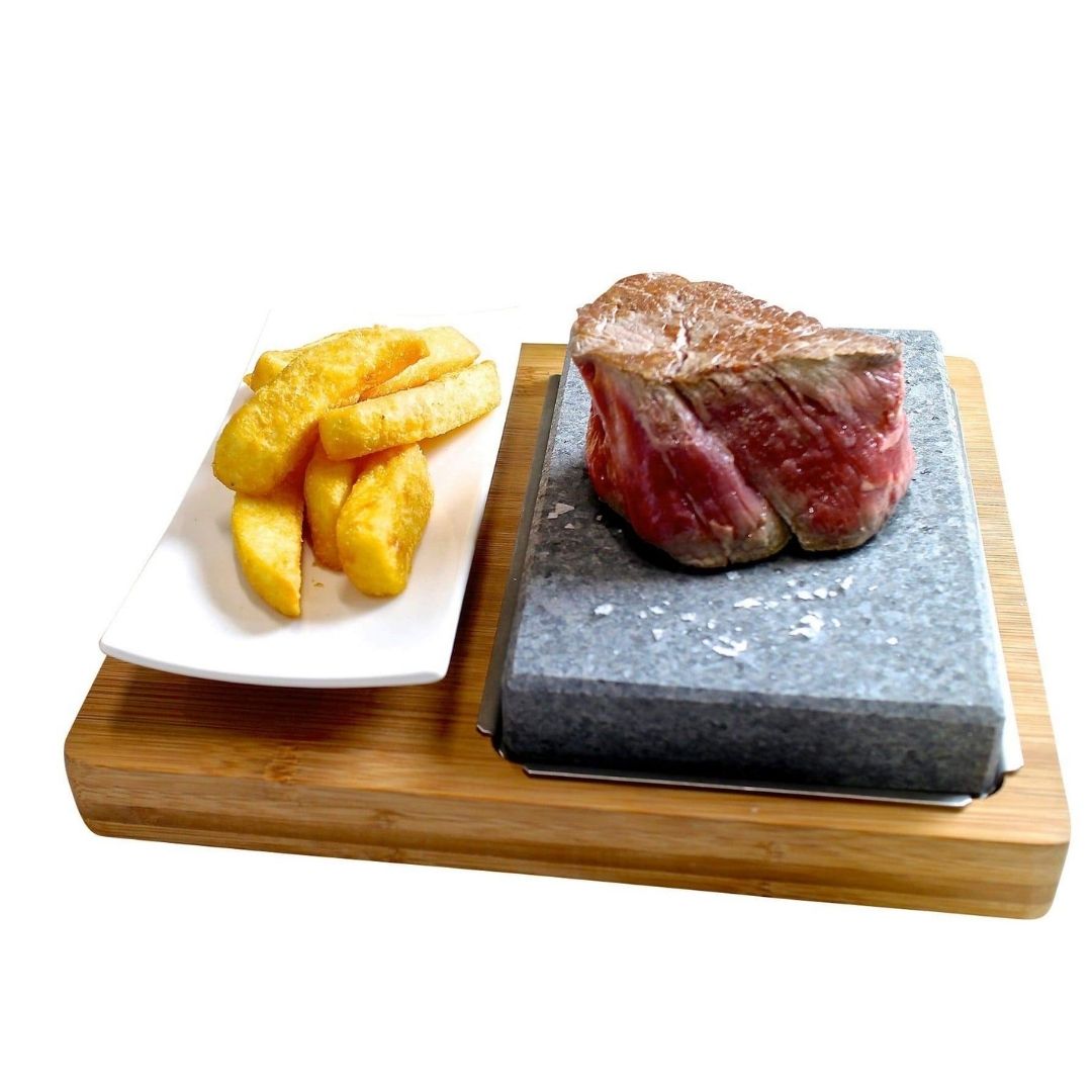 Steak on a sizzling Lava Steak Stone Set with thick-cut fries, stylishly served on GP-9 White Porcelain Side Plates by Black Rock Grill, all atop a wooden board.