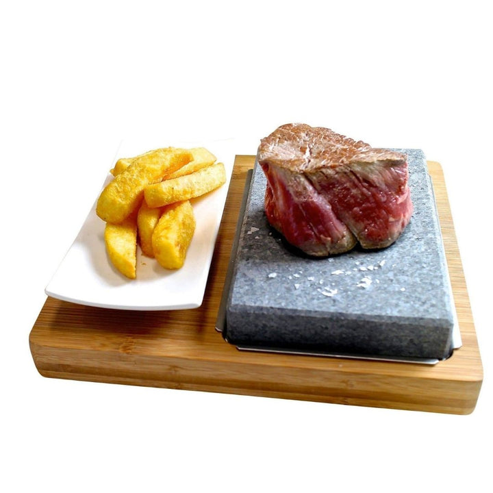 Steak on a sizzling Lava Steak Stone Set with thick-cut fries, stylishly served on GP-9 White Porcelain Side Plates by Black Rock Grill, all atop a wooden board.