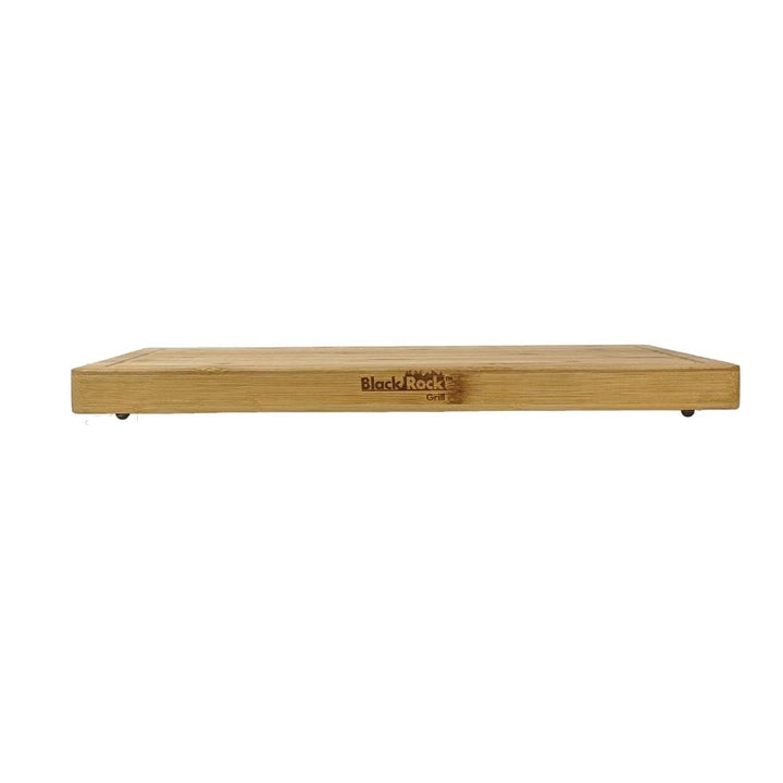 A large wooden serving board, branded Black Rock Grill, is elegantly engraved on the side. This sustainable bamboo chopping board is viewed from a low angle against a white background, blending durability with style.