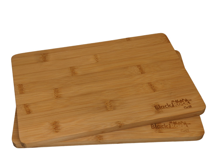 Two Black Rock Grill Wooden Serving Steak Boards, each 30x20x1.2cm, stacked slightly askew and featuring the engraved logo in one corner. Crafted from sustainable bamboo, they boast a smooth, natural wood finish.