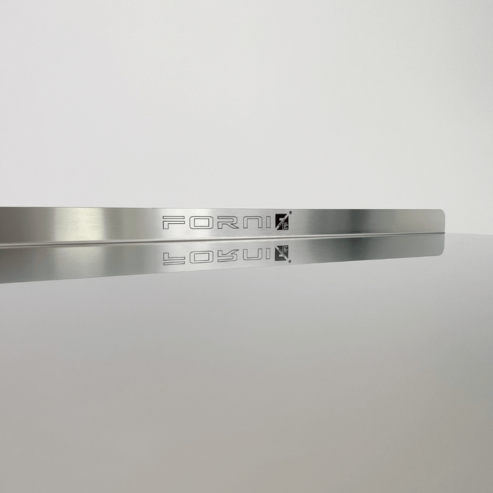 A sleek metallic Effeuno strip sits on a shiny surface, its reflection catching the light. Crafted from AISI 304 stainless steel with FORMI engraved in a modern font, the minimalist design against a soft gray background perfectly complements any pizza-making tool collection.