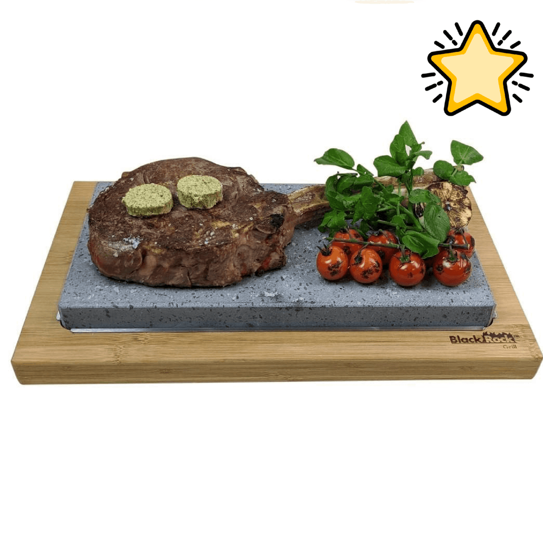 The Black Rock Grill: Steak Stone Set For 2 features a sizzling steak stone with a cooked tomahawk steak topped with herb butter, cherry tomatoes, and fresh greens on a wooden board—a true Black Rock Grill experience.