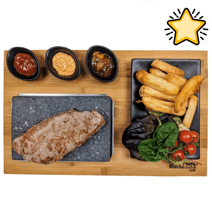 The Black Rock Grill Matt Black Steak Stones Cooking Set by Black Rock Grill is shown with a cooked steak on the stone, three sauces in black bowls, thick-cut fries, cherry tomatoes, leafy greens, and a yellow star graphic in the corner.