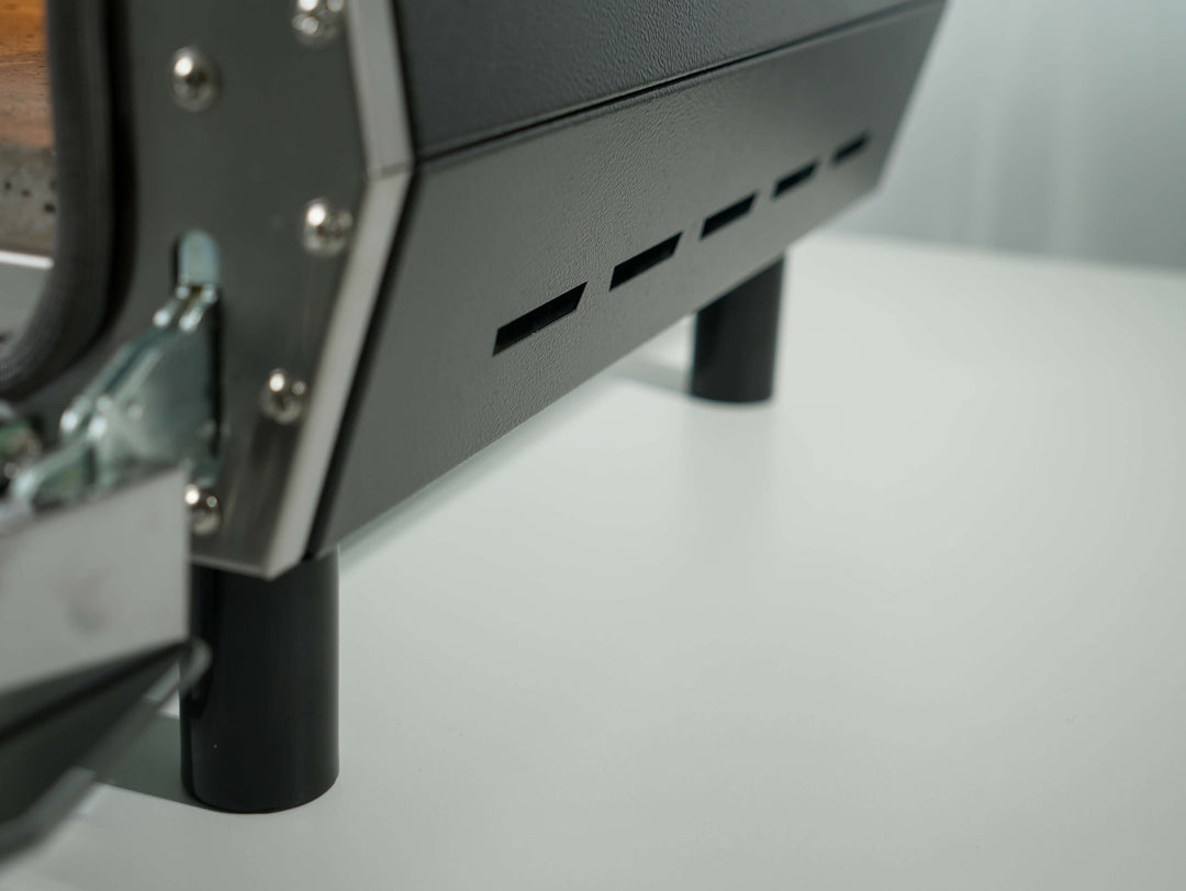 Close-up of the lower part of the Effeuno Pulse Electric Pizza Oven – 948F/509°C Neapolitan oven with vent slots and two cylindrical legs, on a white surface. Features Biscotto Stone. For indoor/outdoor use. Made in Italy.