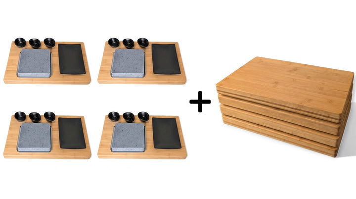 Four Black rock grill lava stone cooking sets on bamboo boards with a lava stone black dipping pots a black side plates sit to the left of a plus symbol and to the right is a stack of four large bamboo serving and cutting boards suggesting to be part of a set.
