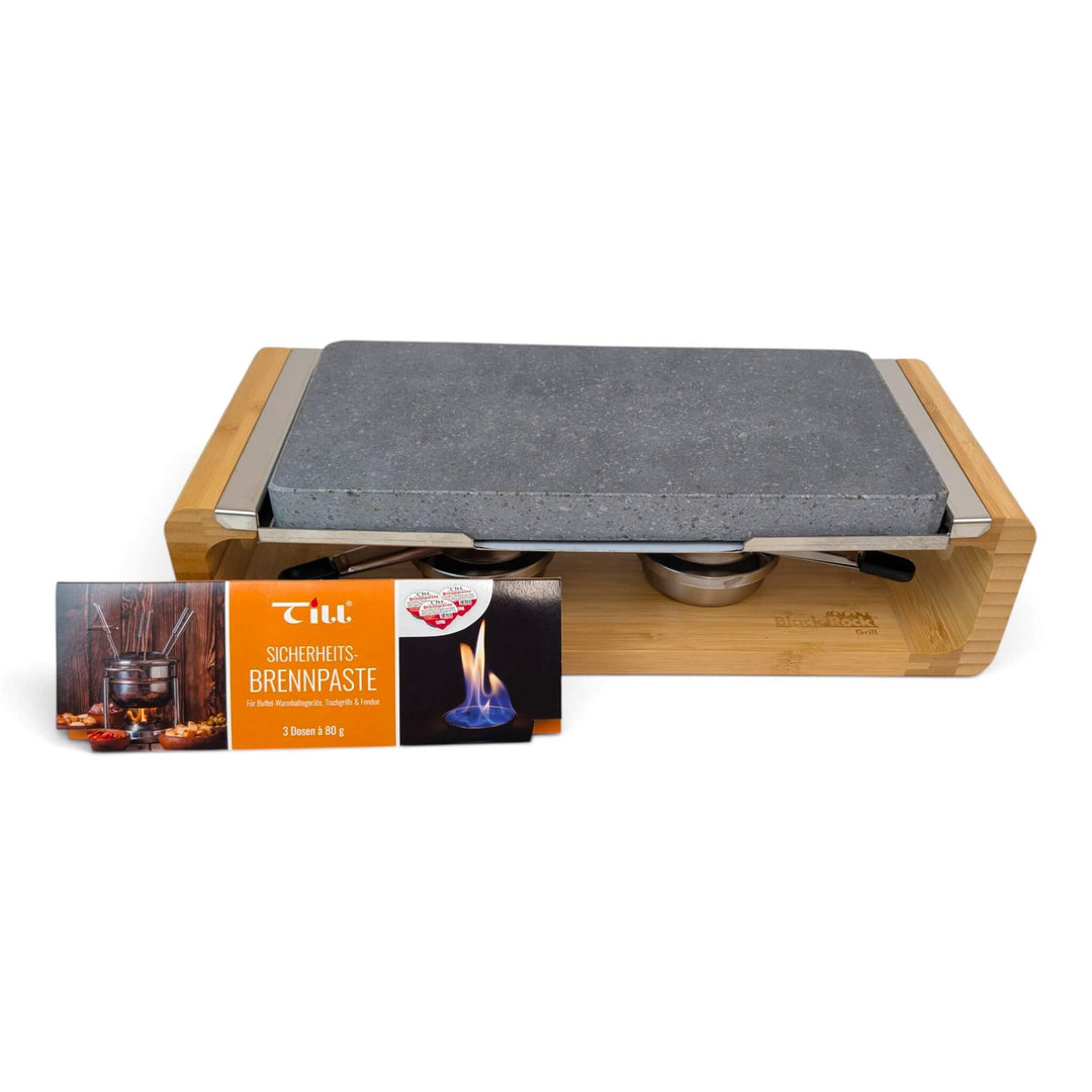 A bamboo-framed tabletop hot lava stone cooking set stove with two stainless steel gel burners to keep the stone hot for longer, with a pack of till brenpaste chaffing gel fuel in the foreground, photographed on a clean white background.