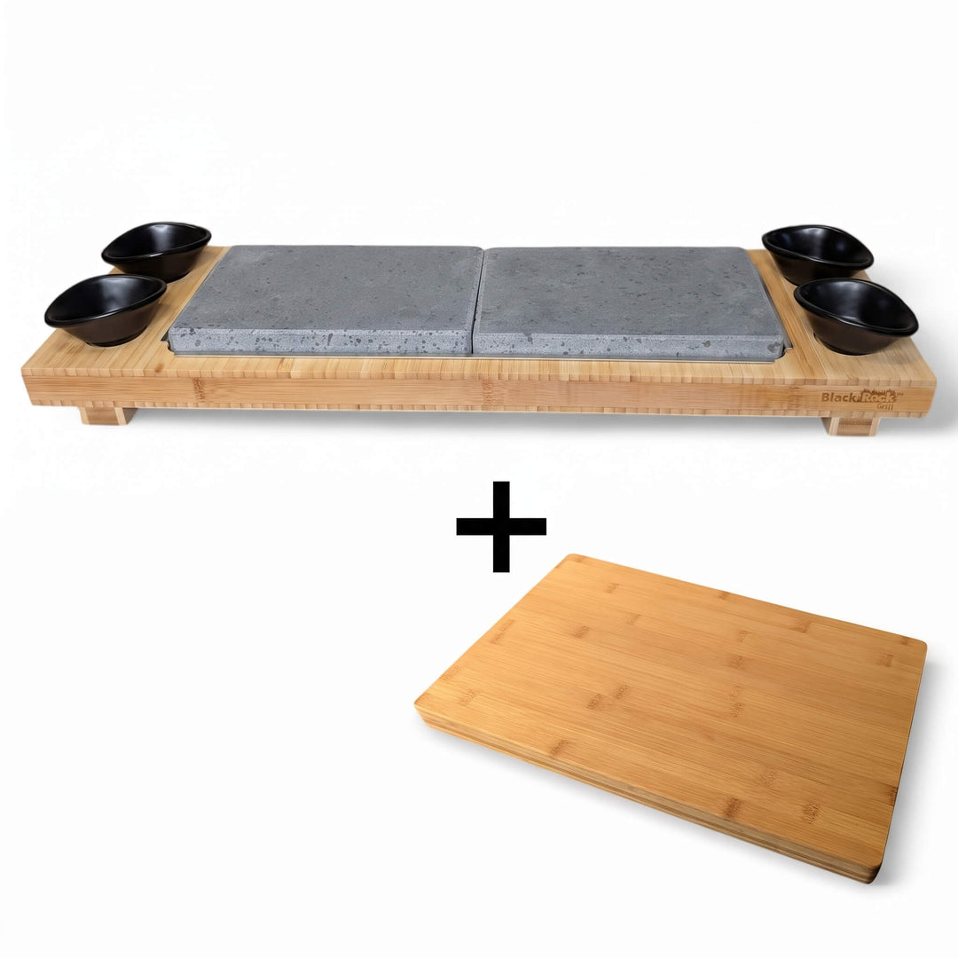 The Black Rock Grill Sharing Lava Sizzler Finishing Warming Platter includes two gray stone slabs, four small black bowls arranged on a premium bamboo serving tray, and comes with a FREE rectangular bamboo board (worth £19.99)—the ideal setup for an elevated dining experience as a sizzler platter or warming stone.