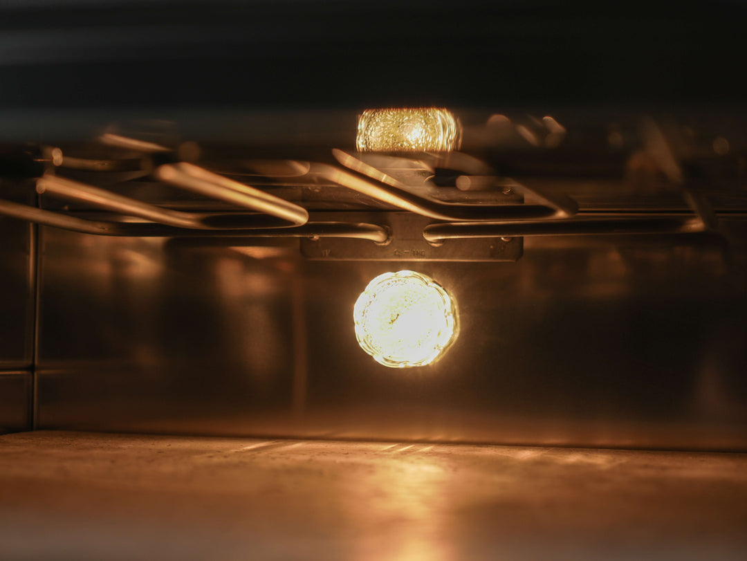 Close-up of the Effeuno Pulse Electric Pizza Oven’s interior, featuring a glowing light, metal racks above, and a reflective finish. This Italian-made oven reaches 948°F (509°C) and includes a Biscotto stone for authentic Neapolitan pizza.