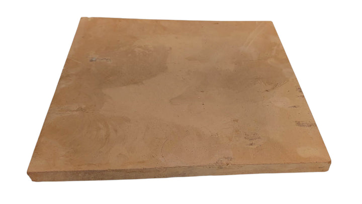 An Effeuno Handmade Italian Biscotto Clay Pizza Stone—artisan-fired with 100% natural materials and a matte finish, featuring unique color variations—is shown angled on a white background, ideal for pizza ovens or Neapolitan pizza setups.