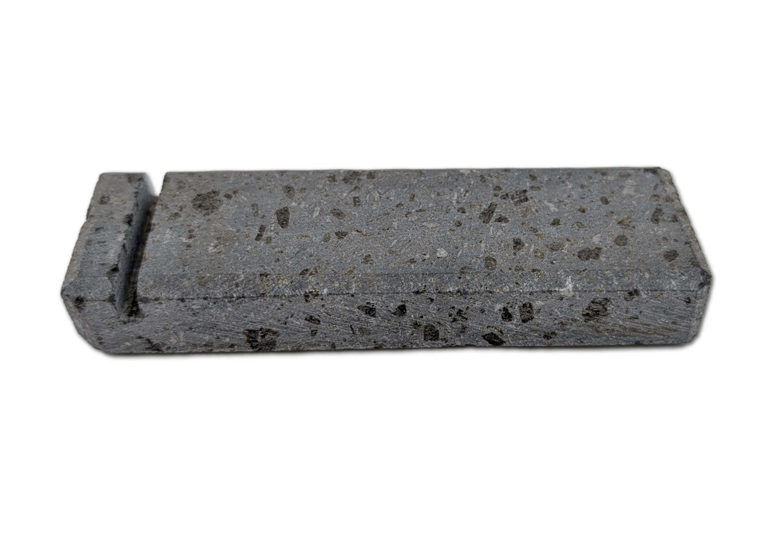 The Black Rock Grill Lava Rock Knife Rest is a limited edition rectangular gray volcanic stone block with black speckles and a raised edge on one end, by Black Rock Grill, shown against a plain white background.