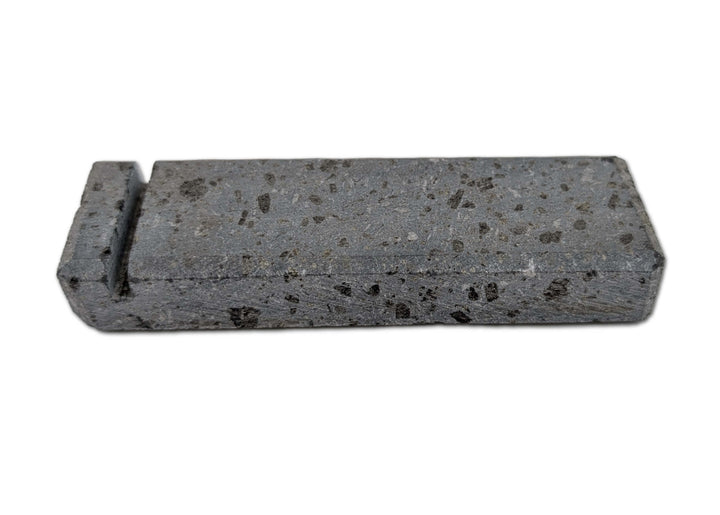 The Black Rock Grill Lava Rock Knife Rest is a limited edition rectangular gray volcanic stone block with black speckles and a raised edge on one end, by Black Rock Grill, shown against a plain white background.