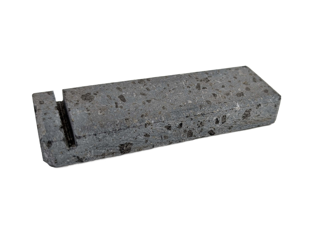 The Black Rock Grill Lava Rock Knife Rest – Limited Edition Table Accessory by Black Rock Grill is a rectangular, speckled gray volcanic stone block with a narrow black groove near one end, shown on a white background.