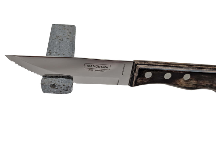 A Black Rock Grill Lava Rock Knife Rest – Limited Edition Table Accessory holds a stainless steel knife with a dark wooden handle, displayed on a white background.