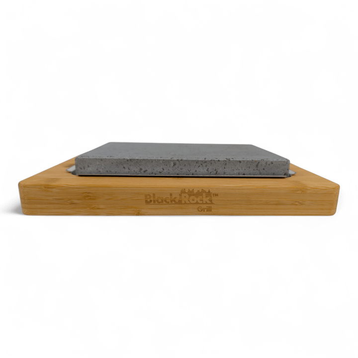 The Black Rock Grill Lava Sizzler Finishing Warming Platter features a rectangular gray stone slab on a bamboo base engraved with the brand name, shown against a white background.