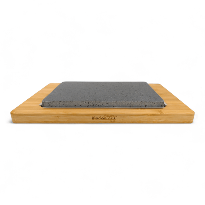 The Large Lava Sizzler Finishing Warming Platter by Black Rock Grill features a black natural lava stone slab set on a light wooden board with rounded edges, and "Black Rock Grill" engraved on the front, shown against a plain white background.