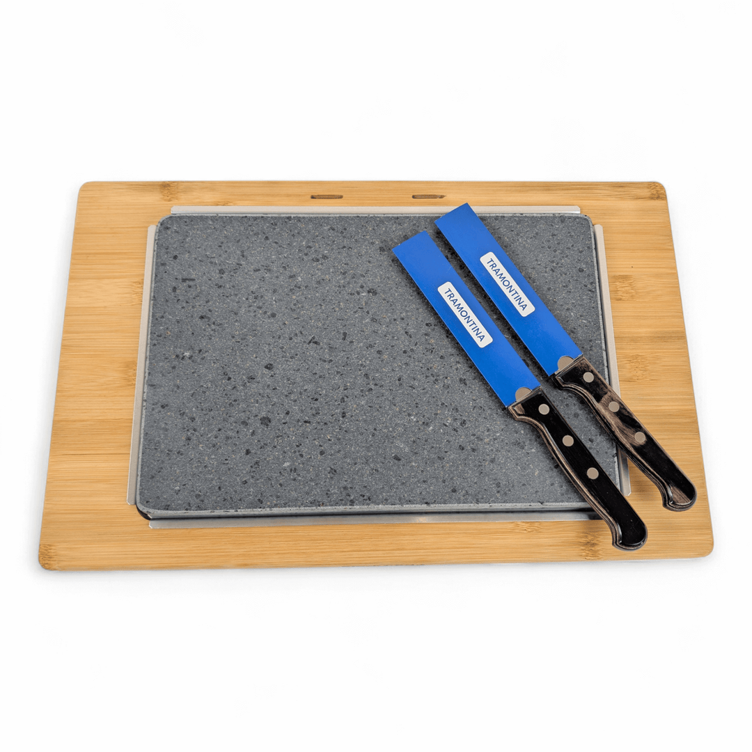 The Black Rock Grill Large Lava Sizzler Finishing Warming Platter features a rectangular bamboo cutting board, a natural lava stone slab for serving, and two large knives with black handles labeled FRONT/MAIN and FRONT/BACK.
