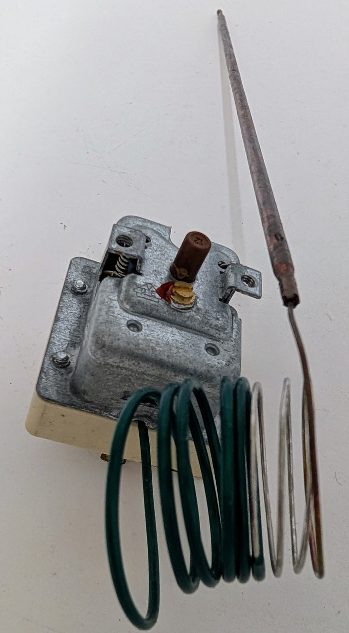 A Black Rock Grill Effeuno 515°C Overheat Reset Switch (P134H/P134HA 450°C, 500°C, 509°C) features a metallic body, coiled green wire, and thin rod—perfect as a replacement part for Effeuno ovens. Shown on a white background.