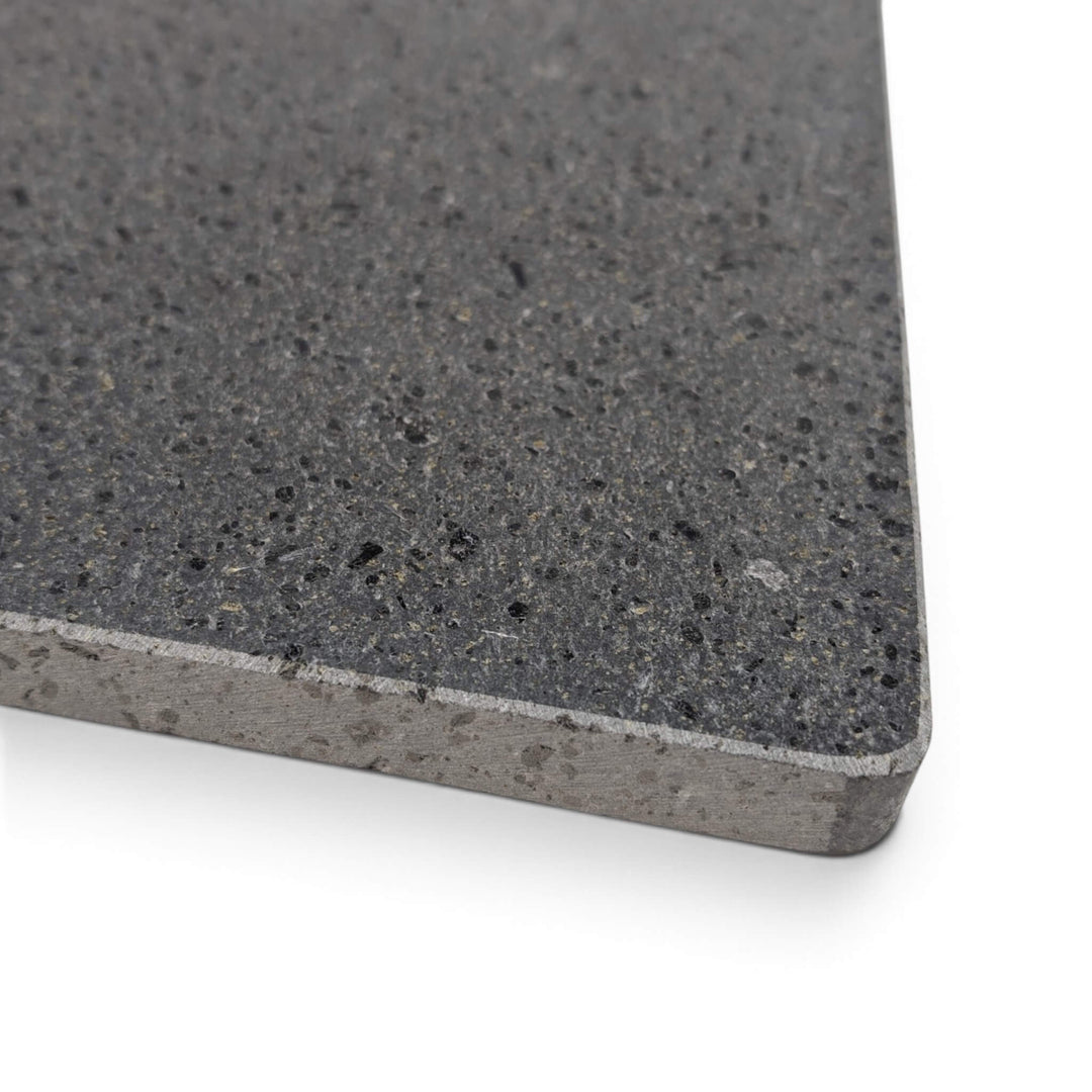 A close-up of a lava pizza stone corner with a beveled edge, shown on a white background.