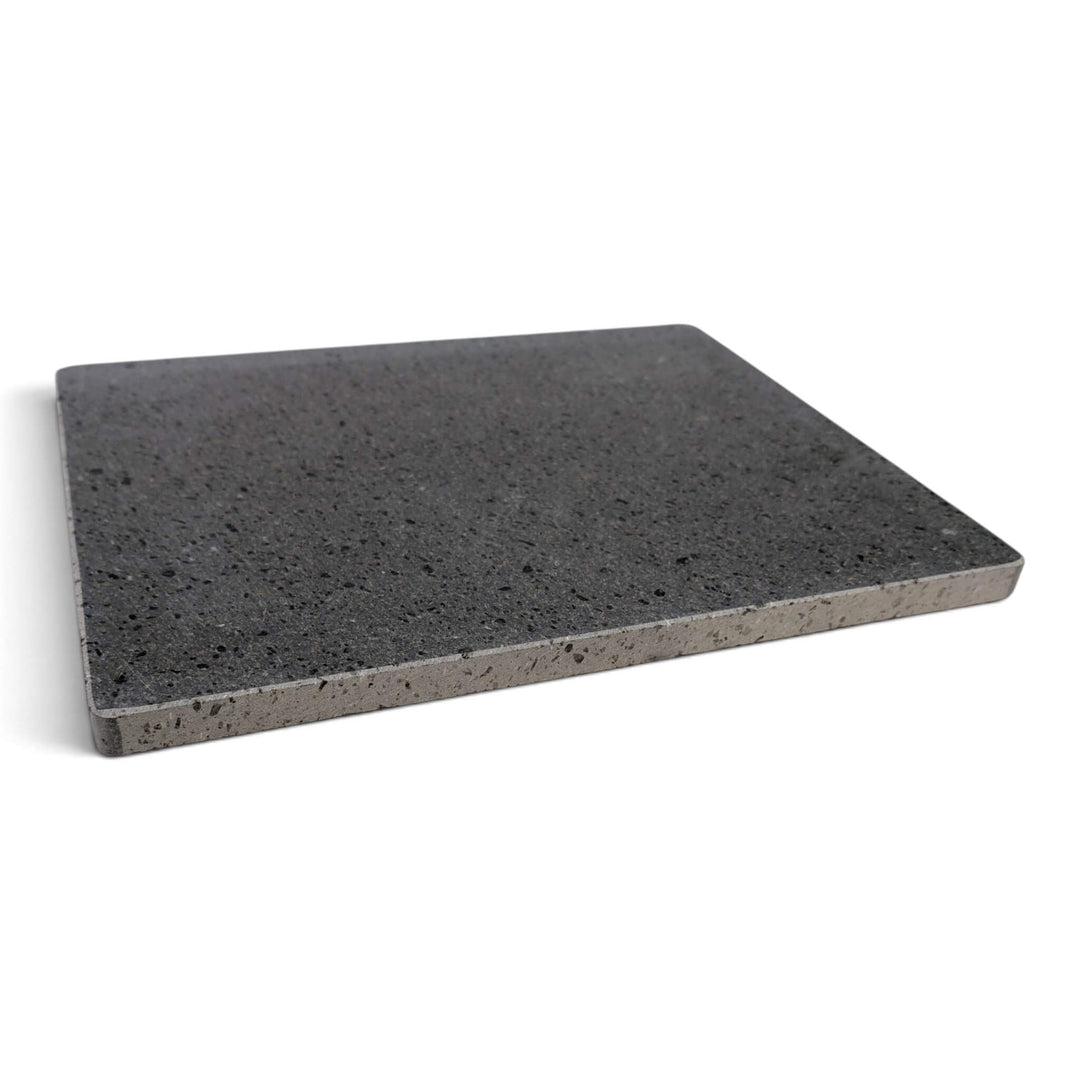 A rectangular lava pizza baking stone with a speckled texture, shown from the side at a slight angle on a white background.