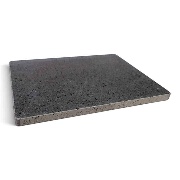 A rectangular lava pizza baking stone with a speckled texture, shown from the side at a slight angle on a white background.