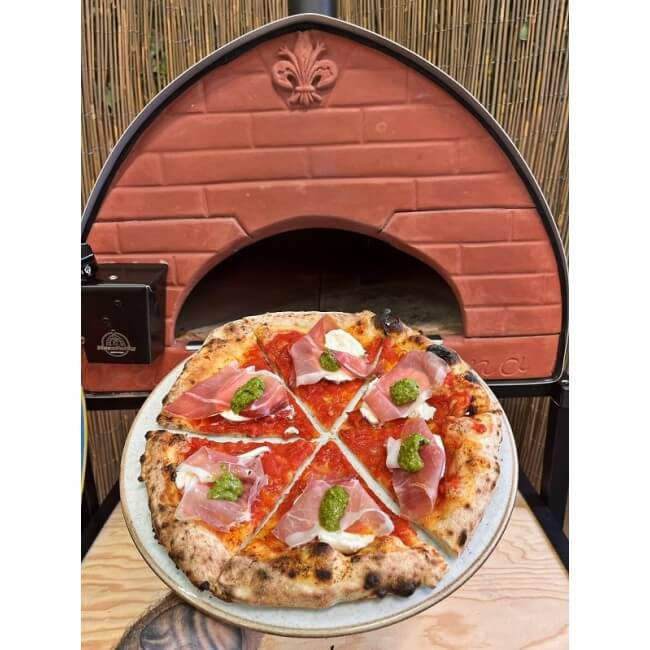 A freshly baked pizza shown directly in front of the Pizza Party Passione dual-fuel outdoor pizza oven.