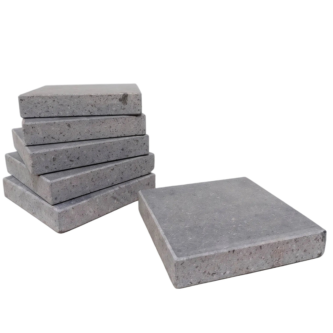 A set of square lava cooking stones, with five stacked on the left and one standing on the right, photographed on a clean white background.