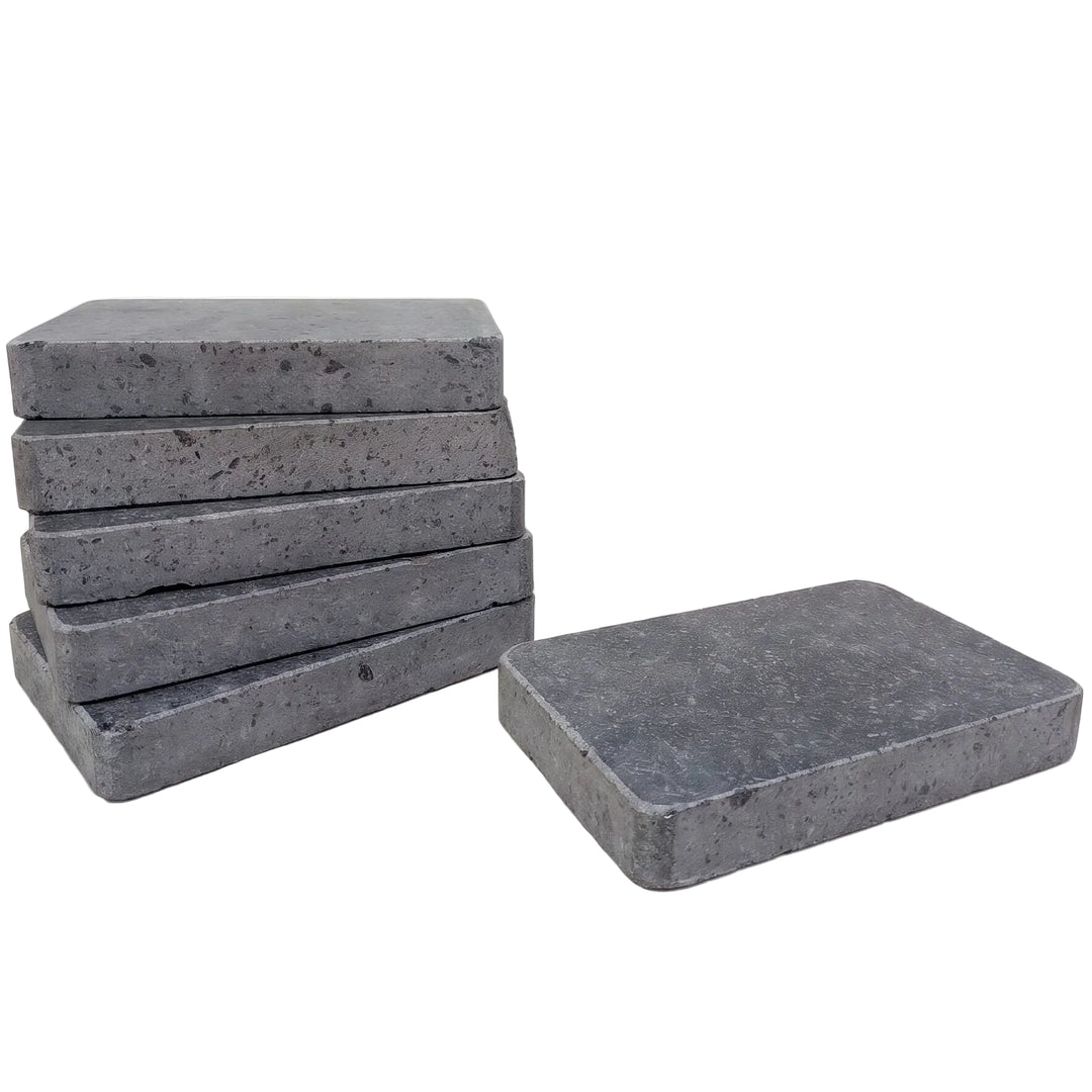 Six rectangular polished lava cooking stones with a speckled texture, with five stacked on the left and one standing on the right, against a plain white background.