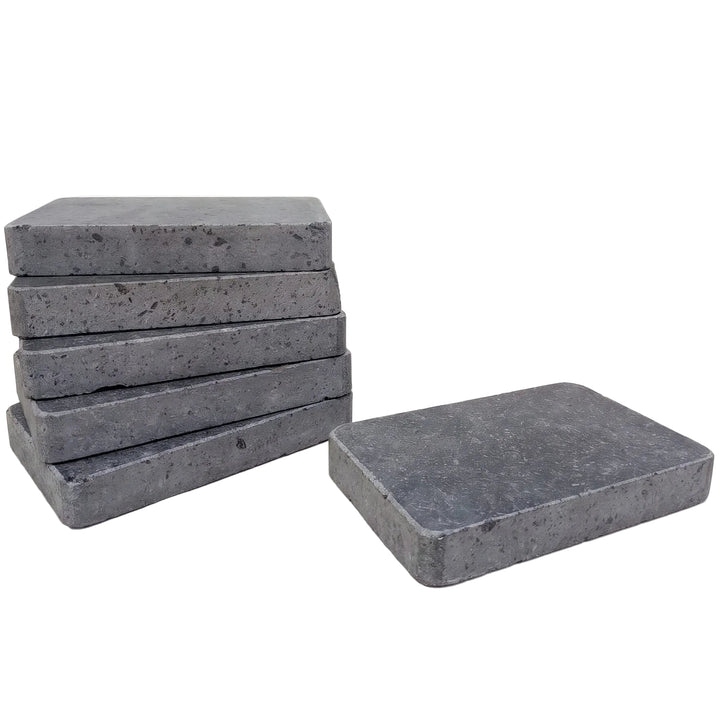 Six rectangular polished lava cooking stones with a speckled texture, with five stacked on the left and one standing on the right, against a plain white background.