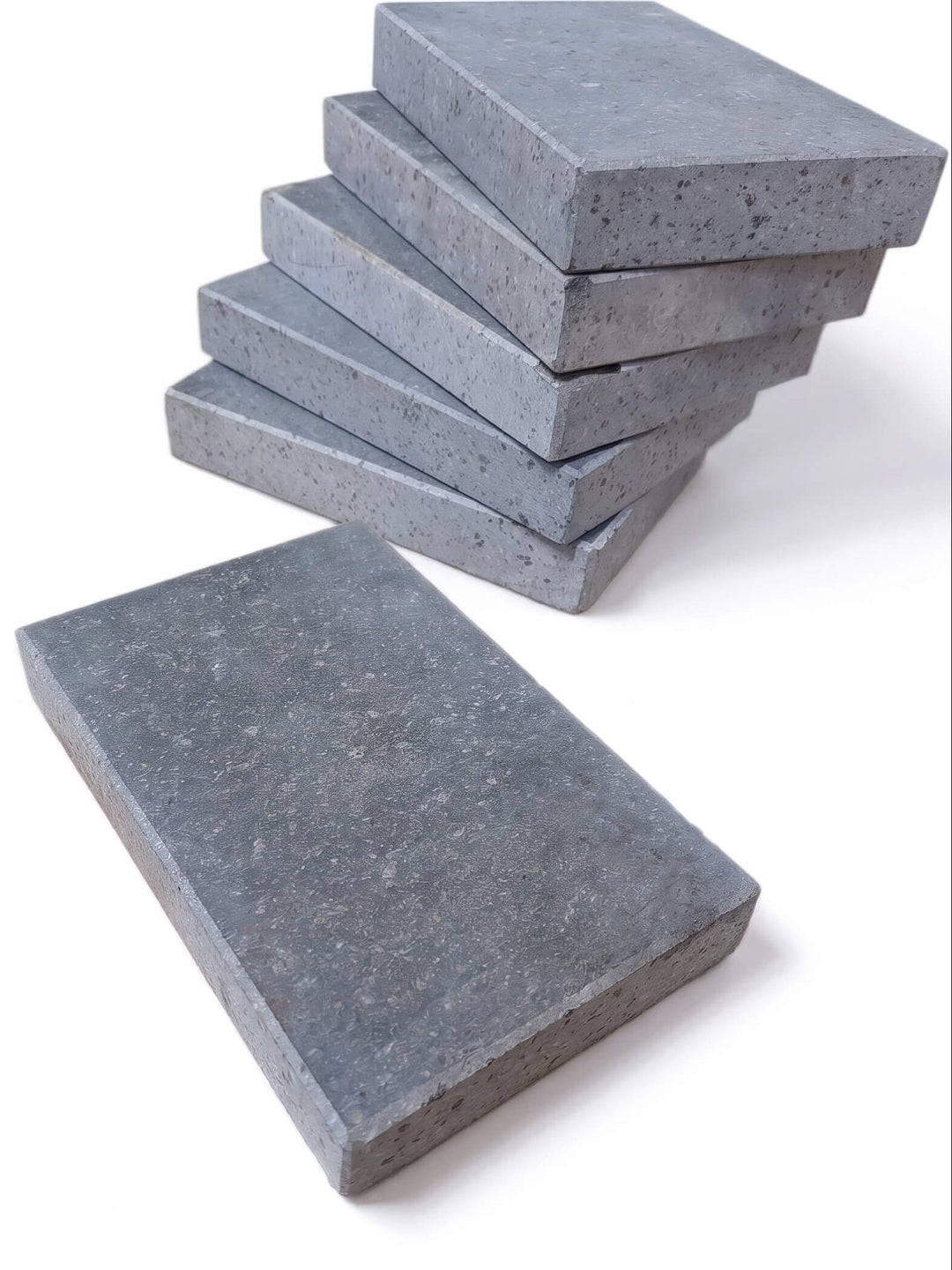A set of rectangular lava cooking stones, with five stacked on the left and one standing on the right, photographed on a clean white background.