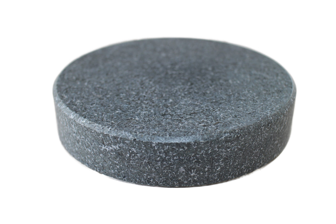 A close-up of a round, flat, textured Round Black Rock Grill Ishiyaki Lava Steak Stone from Black Rock Grill (Case of 6), isolated on a white background.